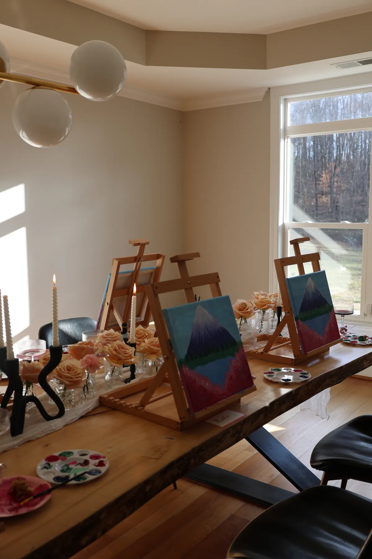 Finished canvases on their easels beside roses in the afternoon light at a Mind & Body Retreats art workshop