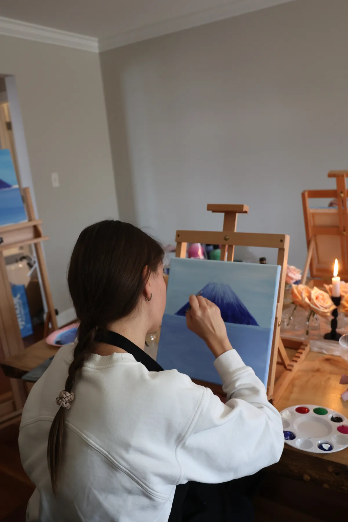 Guest at her easel painting a snow-capped mountain canvas at a Mind & Body Retreats art workshop