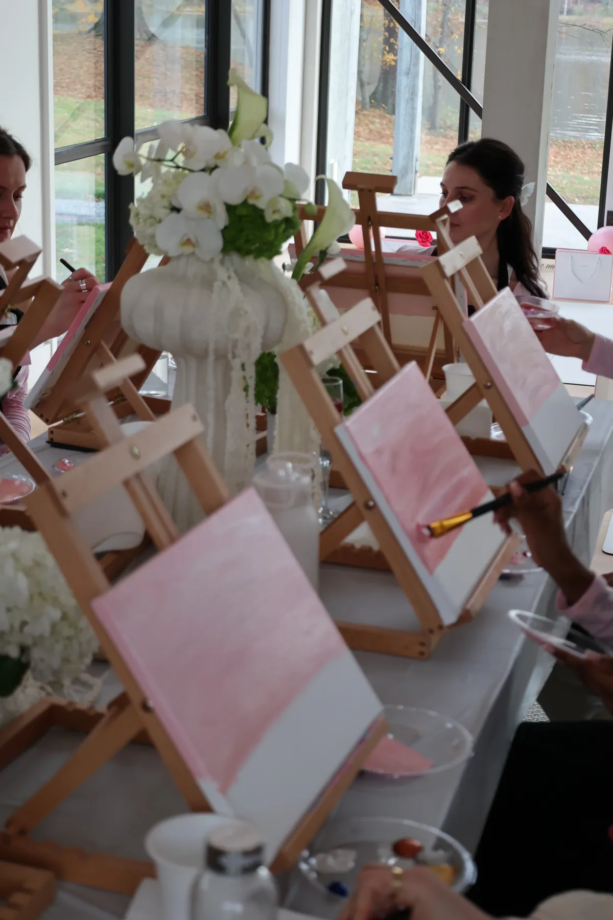 Guests working at their easels among white orchids at a Mind & Body Retreats art workshop