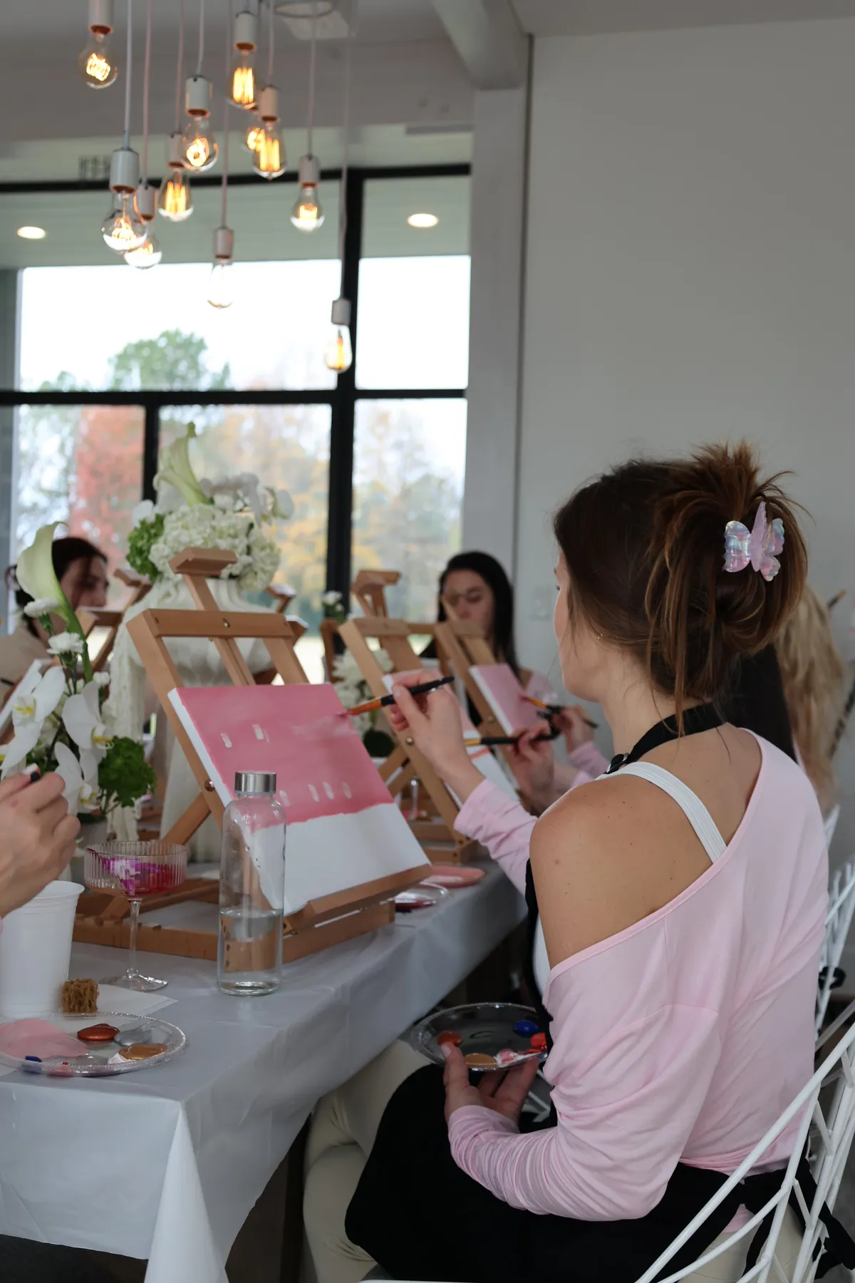 Guests painting pink abstract canvases at a long white table at a Mind & Body Retreats art workshop