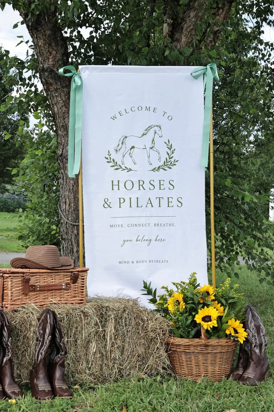 Welcome to Horses & Pilates banner with hay bales, cowboy boots, and sunflowers at a Mind & Body Retreats event in Leesburg, Virginia