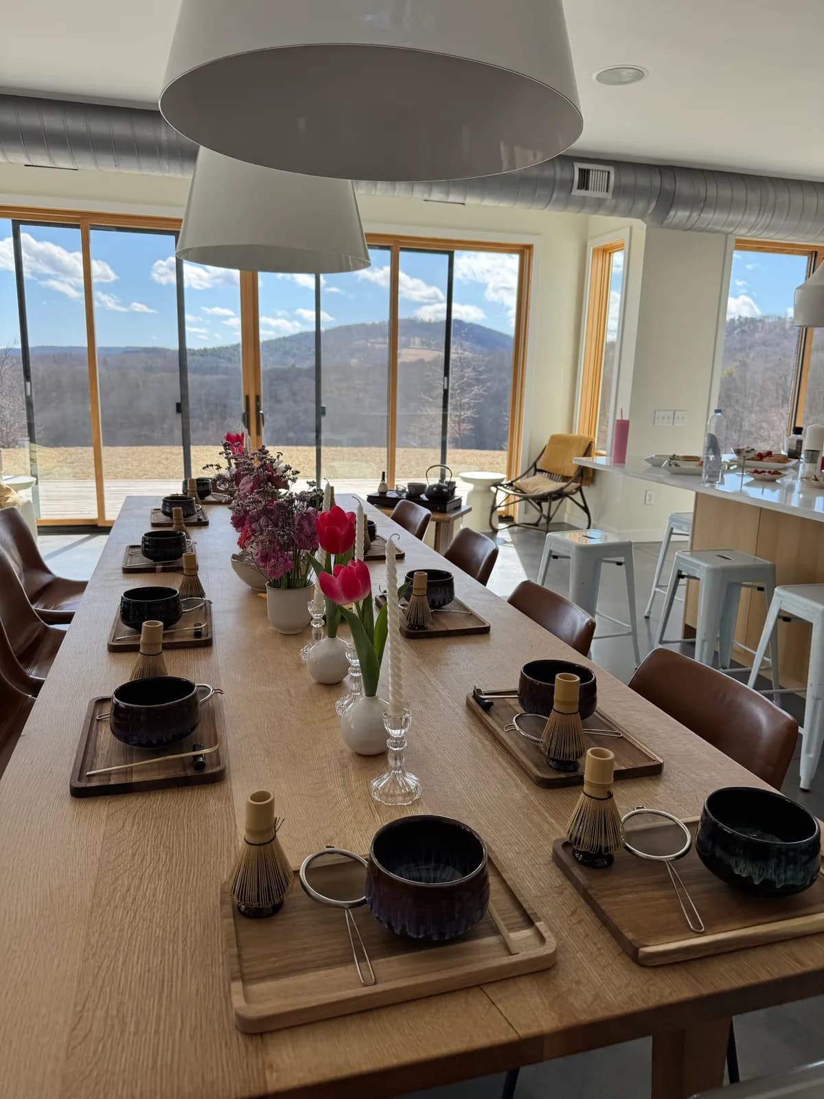 Long table set with a matcha bowl, bamboo whisk, sieve, and scoop at every seat, mountains through the windows, at a Mind & Body Retreats matcha workshop