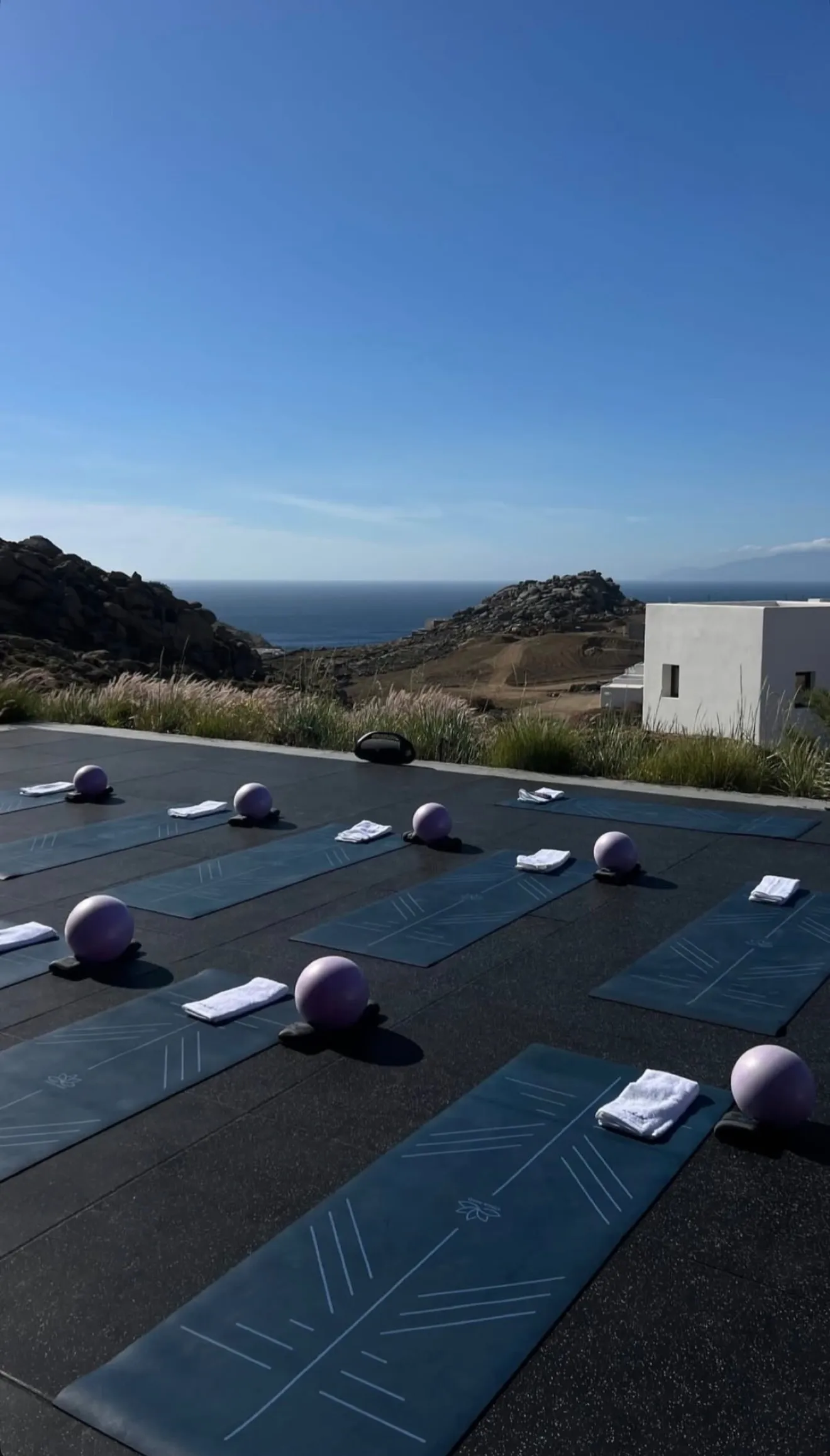 Pilates mats and pink toning balls laid out on a stone terrace above the Aegean at the Mind & Body Retreats Greece retreat